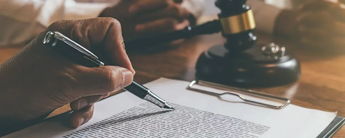 mężczyzna podpisujący dokument na biurku prawnika