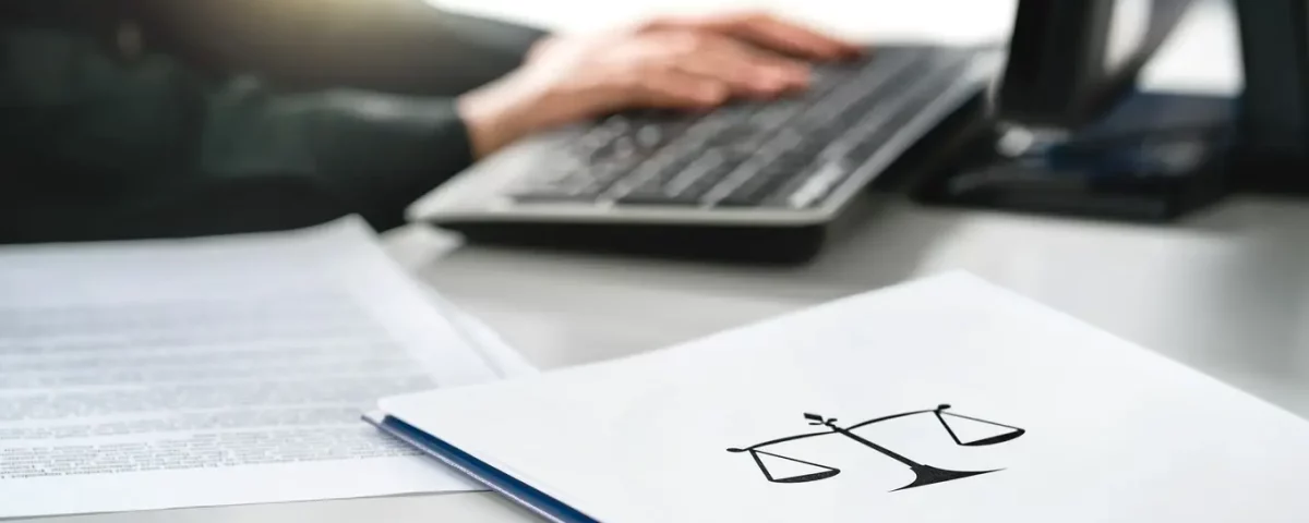 osoba pisząca na laptopie oraz folder z symbolem wagi