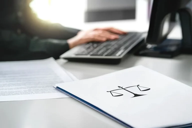 osoba pisząca na laptopie oraz folder z symbolem wagi